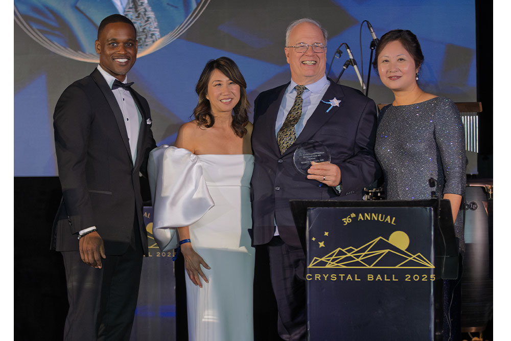Four people at a podium, smiling